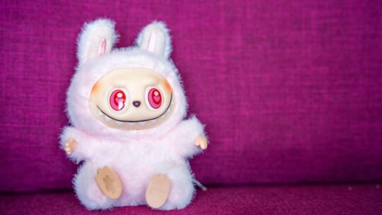 Laubu collectible figure from Pop Mart sitting on soft pink fabric background.