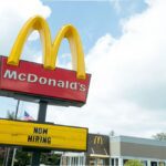 McDonald's golden arches sign with a now hiring message below