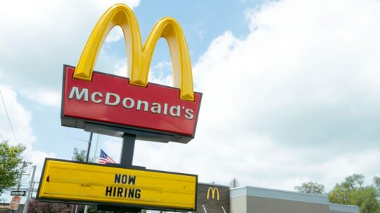 McDonald's golden arches sign with a now hiring message below