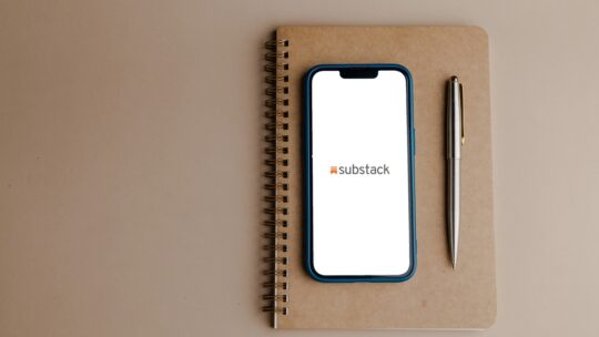 Mobile phone with webpage of US subscription company Substack Inc. on screen in front of business logo.