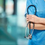 Nurse, woman and arms crossed for cardiology with stethoscope in clinic, support and healthcare. Female person, medical and tool to monitor heart in hospital, medicine and surgeon for treatment