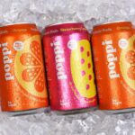 Three cans of Poppi Prebiotic Soda on a bed of ice.