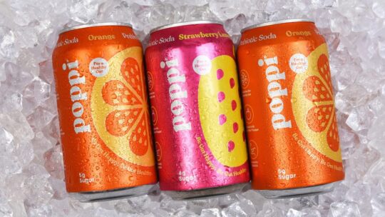 Three cans of Poppi Prebiotic Soda on a bed of ice.
