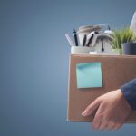 Office worker carrying personal belongings in a box after being fired, unemployment and career concept