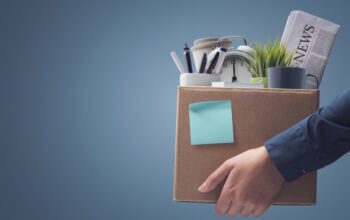 Office worker carrying personal belongings in a box after being fired, unemployment and career concept