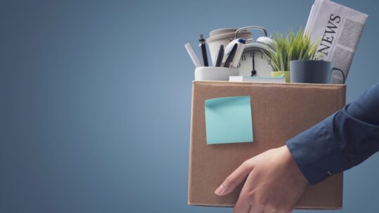 Office worker carrying personal belongings in a box after being fired, unemployment and career concept