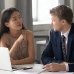 female consultant chatting with a male client. Sitting together at office with computer, discussing project ideas.