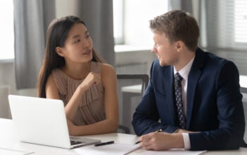 female consultant chatting with a male client. Sitting together at office with computer, discussing project ideas.