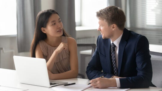 female consultant chatting with a male client. Sitting together at office with computer, discussing project ideas.