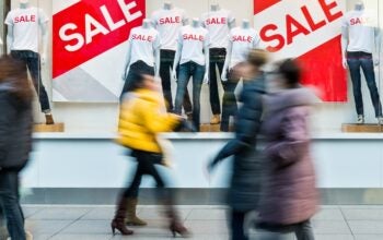 People walking through the window display with text SALE.