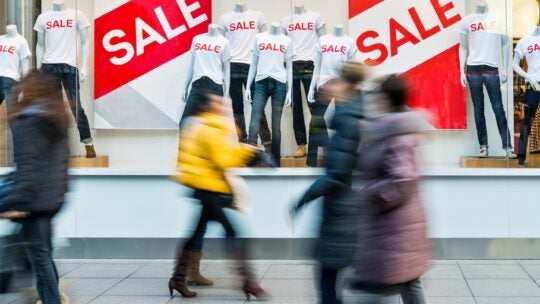 People walking through the window display with text SALE.