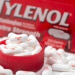 Bottle of Tylenol extra strength with many 500mg pills on white background, most common painkillers and fever reducer medicine in America