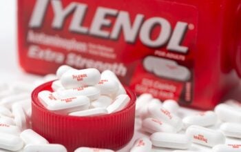 Bottle of Tylenol extra strength with many 500mg pills on white background, most common painkillers and fever reducer medicine in America