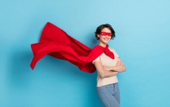 Photo of confident shiny lady dressed red mantle arms crossed cape flying isolated blue color background