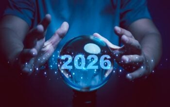 A glowing crystal ball with the year 2026 illuminated inside surrounded by human hands and digital sparkles. This image symbolizes prediction, foresight, planning, and vision for the future.