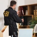 Male FBI agent taking folder from shelf in office, back view