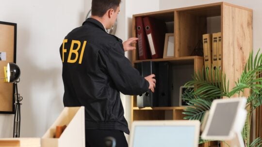 Male FBI agent taking folder from shelf in office, back view