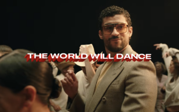 Bad Bunny in an Apple TV commercial for his super bowl halftime performance. He is dancing surrounded by a diverse group of people also dancing. The text says: The World Will Dance.
