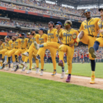 Savannah Bananas baseball team in a kickline along the baseline at a stadium