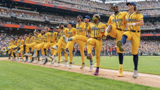 Savannah Bananas baseball team in a kickline along the baseline at a stadium