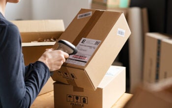 Hands scanning barcode on delivery parcel. Worker scan barcode of cardboard packages before delivery at storage. Woman working in factory warehouse scanning labels on the boxes with barcode scanner.