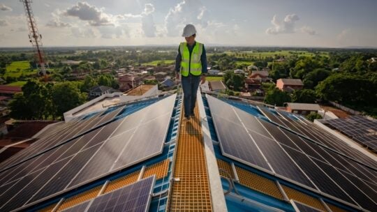 Solar roofing engineering technician working on top of high building, while energy companies are in crisis.