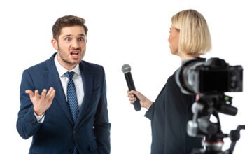 journalist interviewing angry businessman near camera