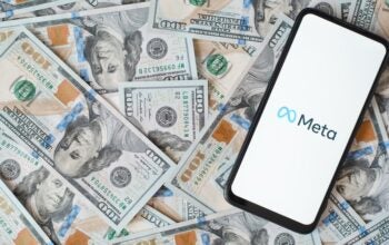 Meta new facebook company logo on smartphone screen, social network mobile application. Top view gadget lying on money background of one hundred dollar bills.
