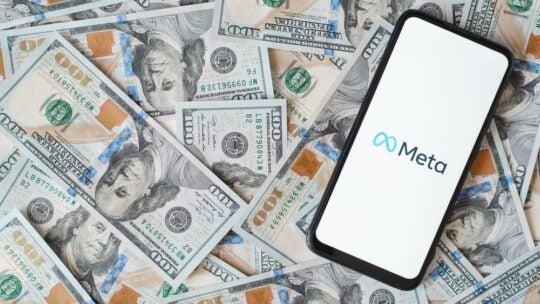 Meta new facebook company logo on smartphone screen, social network mobile application. Top view gadget lying on money background of one hundred dollar bills.