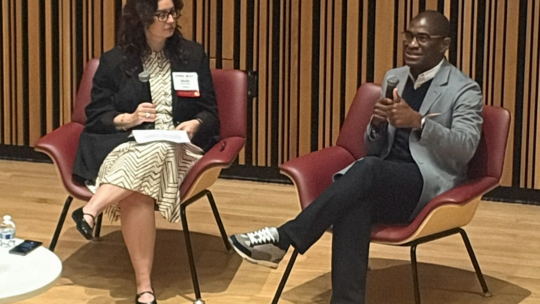 Nicole Schuman and AJ Jones II talking onstage at Mid-Atlantic MarComm Summit in October 2026