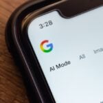 Macro shot of a smartphone screen showing the Google website with "AI Mode" selected, highlighting AI-enhanced search features.