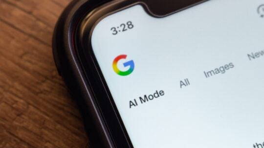 Macro shot of a smartphone screen showing the Google website with "AI Mode" selected, highlighting AI-enhanced search features.